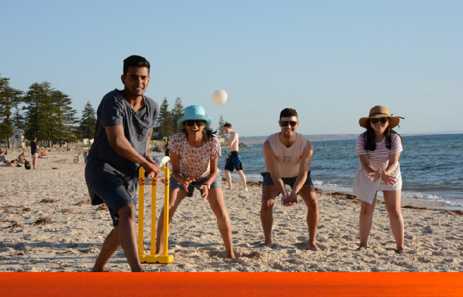 A group of international students and their Australian friends enjoying a game of cricket on the beach in Adelaide